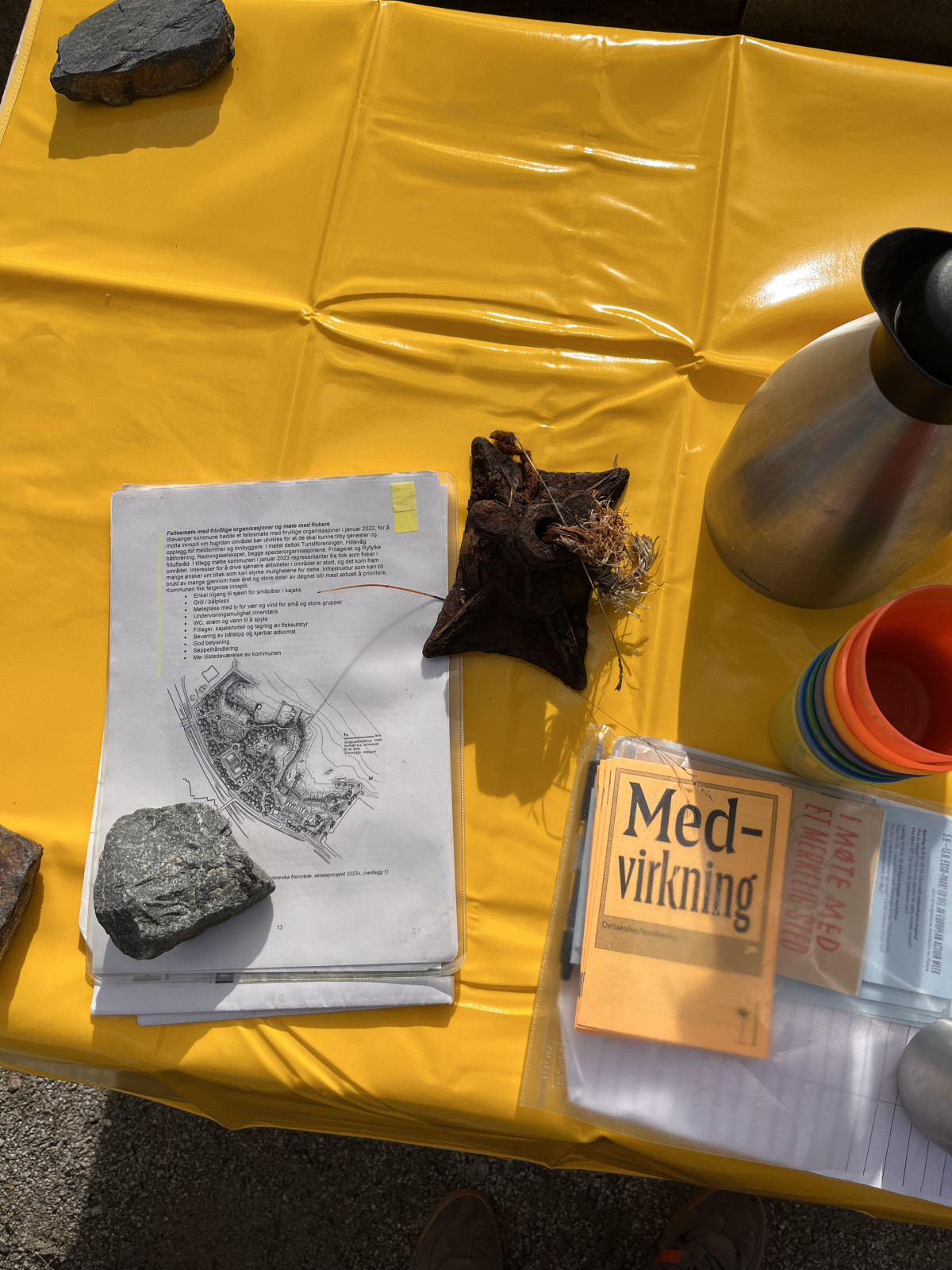 a table, yellow table cloth, papers, a map, zines about participation, coffee, cups